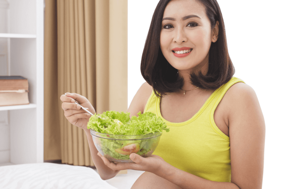 woman wearing yellow top holding clear bowl containing lettuce and tomatoes