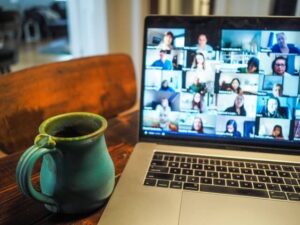 laptop showing virtual meeting mug beside it